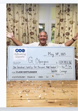 Adjusting Experts client receiving a $124,953.36 water damage claim settlement check
